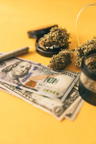 Cannabis in Economics. Sativa THC CBD. Joint weed. Marijuana weed bud and grinder. Indica medical health. Marijuana bud and banknotes of dollars. Cannabis money black market. Vertical shot .
