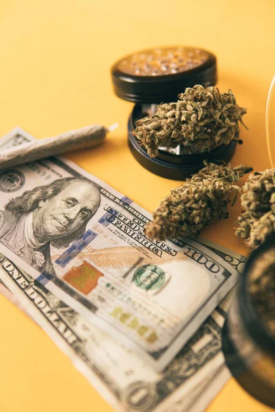 Marijuana weed bud and grinder. Indica medical health. Marijuana bud and banknotes of dollars. Cannabis money black market. Money weed. Cannabis in Economics. Joint weed. Vertical shot .