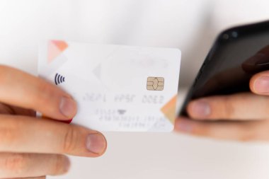 Genç adamın akıllı telefon kullanarak el ele tutuşması ve sosyal online alışveriş konseptiyle sabah vakti kredi kartı tutuşu. İş yerinde ödemeler çevrimiçi akıllı telefon.