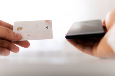 Sabah ışığında online alışveriş konsepti. Genç adamın akıllı telefon kullanarak el ele tutuşması ve sosyal ödemeyle birlikte iş yerinde internet üzerinden akıllı telefon kullanması..