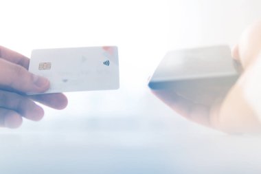 İş yerinde ödemeli online akıllı telefon. Sabah ışığında online alışveriş konsepti. Akıllı telefon kullanan ve sosyal güvenlik kartı tutan genç bir adamın el ele tutuşması.