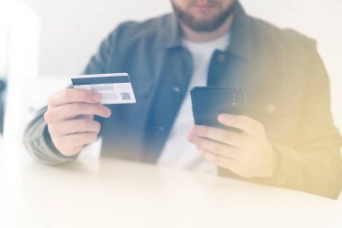 Ödeme internet üzerinden akıllı telefon işyerinde. Kredi kartıyla internet alımı ve geçmişi bulanık bir şekilde evde oturan akıllı bir telefon. İnternetten alışveriş için el kredi kartı. Web alışverişi .