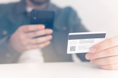 Ödeme internet üzerinden akıllı telefon işyerinde. Kredi kartıyla internet alımı ve geçmişi bulanık bir şekilde evde oturan akıllı bir telefon. İnternetten alışveriş için el kredi kartı. Web alışverişi .
