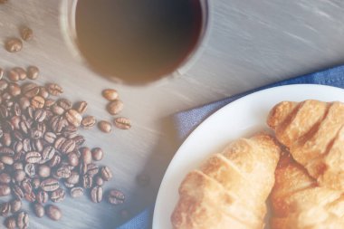 Kahve fincanı ve ahşap arka planda taze pişmiş kruvasan. Üst Görünüm.