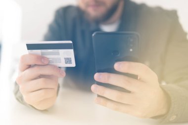 Kredi kartıyla internet alımı ve geçmişi bulanık bir şekilde evde oturan akıllı bir telefon. Ödeme internet üzerinden akıllı telefon işyerinde. İnternetten alışveriş için el kredi kartı. Web alışverişi .
