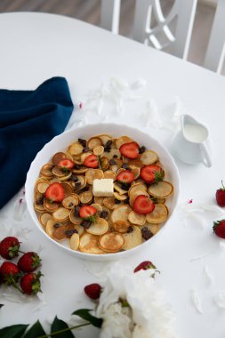 Sağlıklı kahvaltı konsepti, beyaz tabakta çilek ve yaban mersini reçeli ahşap rustik masa üzerine Amerikan sabah yemeği yığını - krep veya börek ile süslenmiş krep