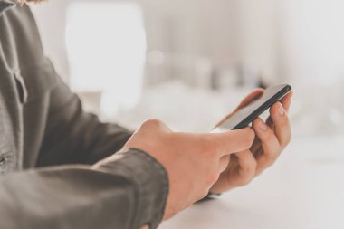 Ödeme internet üzerinden akıllı telefon işyerinde. İnternetten alışveriş için el kredi kartı. İnternet alışverişi. Kredi kartıyla internet alımı ve geçmişi bulanık bir şekilde evde oturan akıllı bir telefon..