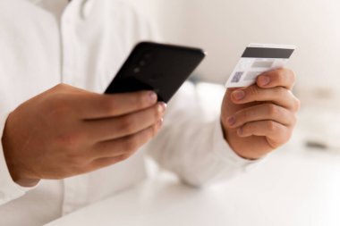 Kredi kartı ve iş adamı elleri akıllı telefon kullanıyor ve elinde sosyal güvenlik kartı tutuyor.