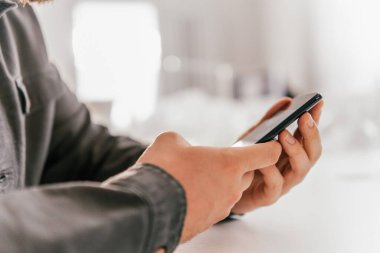 Ödeme internet üzerinden akıllı telefon işyerinde. Kredi kartıyla internet alımı ve geçmişi bulanık bir şekilde evde oturan akıllı bir telefon..