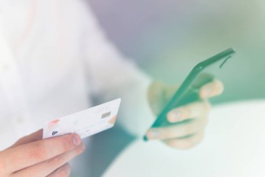İş yerinde ödemeli online akıllı telefon. Sabah ışığında online alışveriş konsepti. Akıllı telefon kullanan ve sosyal güvenlik kartı tutan genç bir adamın el ele tutuşması.