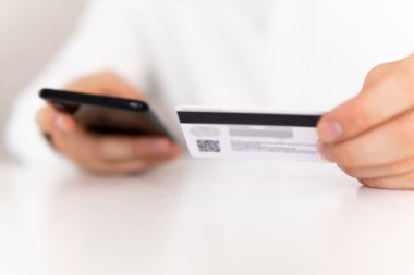 Genç adamın akıllı telefon kullanarak el ele tutuşması ve sosyal online alışveriş konseptiyle sabah vakti kredi kartı tutuşu. İş yerinde ödemeler çevrimiçi akıllı telefon.