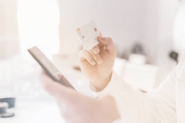 Web alışverişi yapan genç adama yakın çekim. Çevrimiçi ödeme, ödemeler iş yerinde online akıllı telefon alışverişi. İnternetten alışveriş yapmak için kredi kartı. Adamın elleri kredi kartını tutuyor.