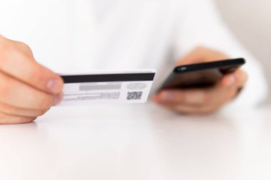 İş yerinde ödemeli online akıllı telefon. Akıllı telefon kullanan ve sosyal online alışveriş konseptiyle kredi kartı tutan genç bir adamın el ele tutuşması..