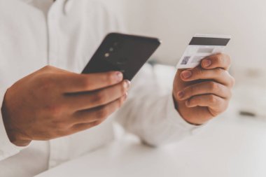 Online alışveriş için akıllı telefon kullanıyor. Sabah ışığında online alışveriş konsepti. Çevrimiçi ödeme, kredi kartı ve iş adamı elleri akıllı telefon kullanıyor ve sosyal kartı elinde tutuyor