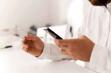 İnternet üzerinden alışveriş yapmak için kredi kartı tutan bir adamın elleri. İnternet alışverişi. Çevrimiçi ödeme, Ödeme yapan genç adamın kapatılması iş yerinde online alışveriş akıllı telefonu.
