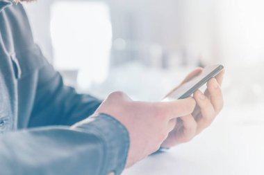 İnternetten alışveriş için el kredi kartı. İnternet alışverişi. Kredi kartıyla internet alımı ve geçmişi bulanık bir şekilde evde oturan akıllı bir telefon. İş yerinde online alışveriş akıllı telefonu ödemesi.