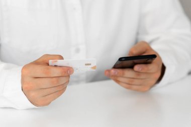 İnternetten alışveriş, adam mutlu. Kredi kartı tutan ve cep telefonu kullanan, kredi kartı ve akıllı telefon kullanan, bulanık geçmişi olan, evde oturan elleri kapatın..