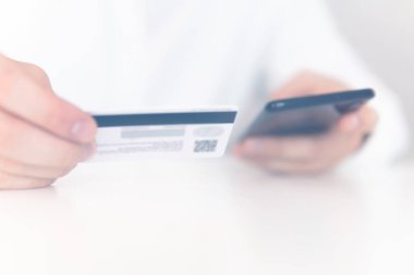 İş yerinde ödemeli online akıllı telefon. Sabah ışığında online alışveriş konsepti. Akıllı telefon kullanan ve sosyal güvenlik kartı tutan genç bir adamın el ele tutuşması.