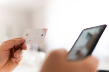 Genç adamın akıllı telefon kullanarak el ele tutuşması ve sosyal online alışveriş konseptiyle sabah vakti kredi kartı tutuşu. İş yerinde ödemeler çevrimiçi akıllı telefon.