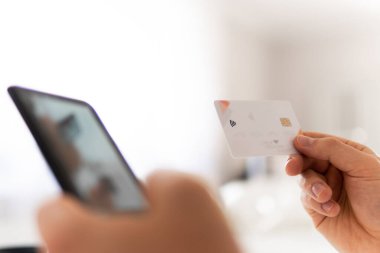 İş yerinde ödemeli online akıllı telefon. Sabah ışığında online alışveriş konsepti. Akıllı telefon kullanan ve sosyal güvenlik kartı tutan genç bir adamın el ele tutuşması.