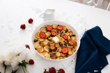 Krepler ya da sağlıklı kahvaltı konsepti olan börekler, Amerikan ahşap sofrasında beyaz tabakta çilek ve yaban mersini reçeli çeşitli sabah yemekleri süslenmiş. -