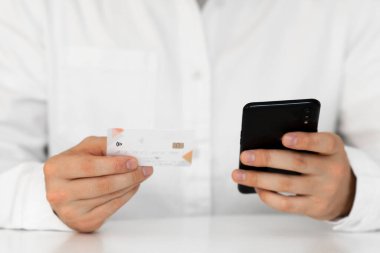 Akıllı telefon kullanan ve sosyal güvenlik kamerasında Ödeme yapan genç adamın iş yerinde online akıllı telefon yapmasını sağlayan eller. Sabah ışığında online alışveriş kavramı.