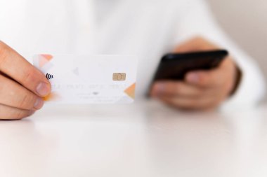 Akıllı telefon kullanan ve sosyal ödemeli akıllı telefondan iş yerinde akıllı telefon kullanan genç bir adamın el ele tutuşması. Sabah ışığında online alışveriş kavramı.