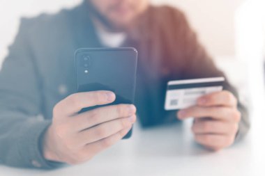 Ödeme internet üzerinden akıllı telefon işyerinde. Kredi kartıyla internet alımı ve geçmişi bulanık bir şekilde evde oturan akıllı bir telefon. İnternetten alışveriş için el kredi kartı. Web alışverişi .
