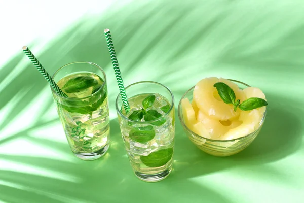 Pineapple juice with palm leaves on green — Stock Photo, Image