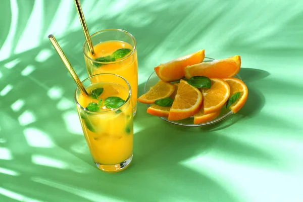 Orange juice with palm leaves on green