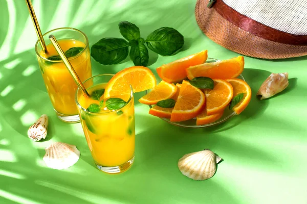 Orange juice with palm leaves on green