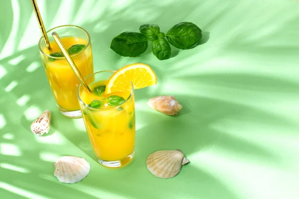 Orange juice with palm leaves on green