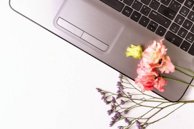 Laptop ve çiçeklerle dolu beyaz bir masa. Serbest İşyeri.