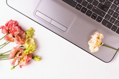 Laptop ve çiçeklerle dolu beyaz bir masa. Serbest İşyeri.