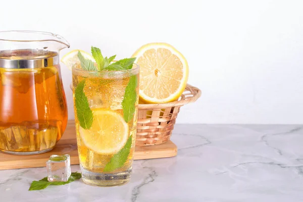 Szklanka mrożonej herbaty z mięty i cytryny na stole marmurowym. Zimny napój. — Zdjęcie stockowe