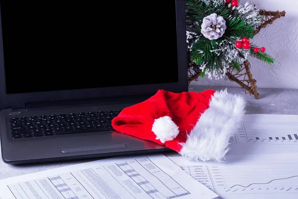 Dizüstü bilgisayar ve grafiklerile masaüstü. Noel Baba şapkası 