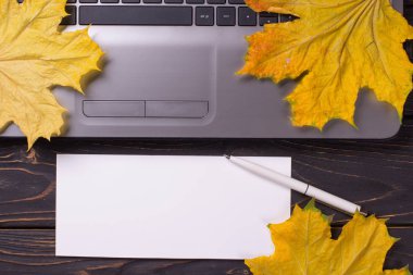 Sonbahar yapraklı, siyah ahşap arka planda dizüstü bilgisayar. Akçaağaç.