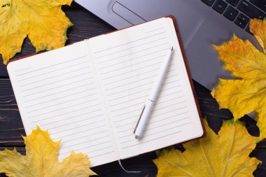 Sonbahar yapraklı, siyah ahşap arka planda dizüstü bilgisayar. Akçaağaç.