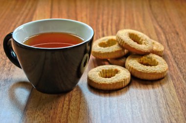 Bir fincan çay ve kurabiye ahşap bir masa üzerinde