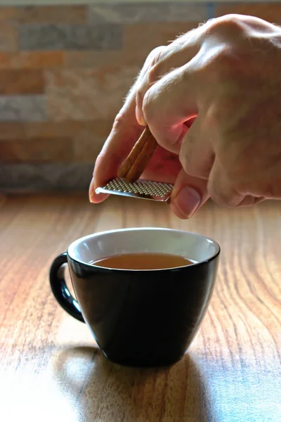 Closeup Hands Grating Cinnamon Cup Tea — Stock Photo, Image