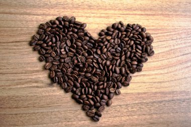 Kahve çekirdekleri ahşap bir masa üzerinde yapılan kalp