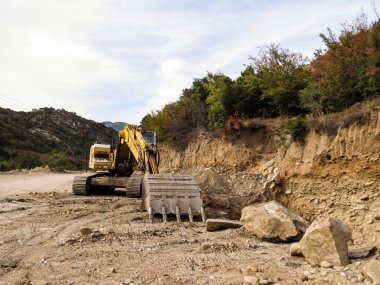 Kazı makinesi, yol genişletme, baraj inşaatı. Yol genişletme ve baraj inşaatı için nehir ağzı yakınında çalışan kazıcı. Ağır makineler iş başında, altyapıyı şekillendiriyor, su akışını kontrol ediyor ve Yunanistan 'da rezervuar inşa ediyor.