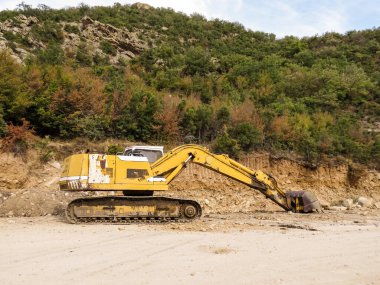 Kazı makinesi, yol genişletme, baraj inşaatı. Yol genişletme ve baraj inşaatı için nehir ağzı yakınında çalışan kazıcı. Ağır makineler iş başında, altyapıyı şekillendiriyor, su akışını kontrol ediyor ve Yunanistan 'da rezervuar inşa ediyor.
