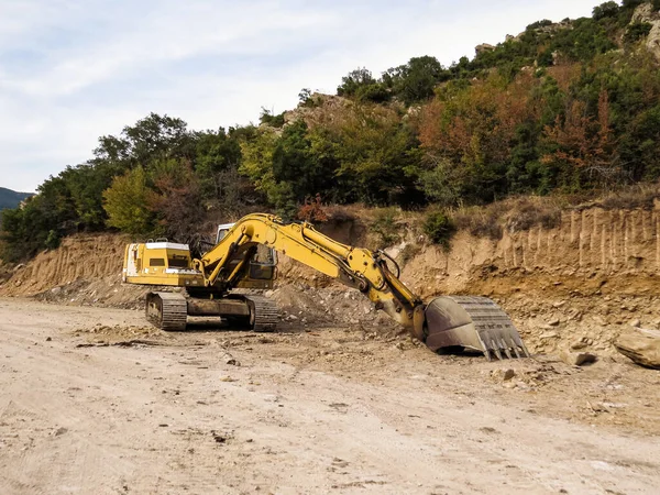 Kazı makinesi, yol genişletme, baraj inşaatı. Yol genişletme ve baraj inşaatı için nehir ağzı yakınında çalışan kazıcı. Ağır makineler iş başında, altyapıyı şekillendiriyor, su akışını kontrol ediyor ve Yunanistan 'da rezervuar inşa ediyor.