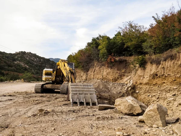 Kazı makinesi, yol genişletme, baraj inşaatı. Yol genişletme ve baraj inşaatı için nehir ağzı yakınında çalışan kazıcı. Ağır makineler iş başında, altyapıyı şekillendiriyor, su akışını kontrol ediyor ve Yunanistan 'da rezervuar inşa ediyor.