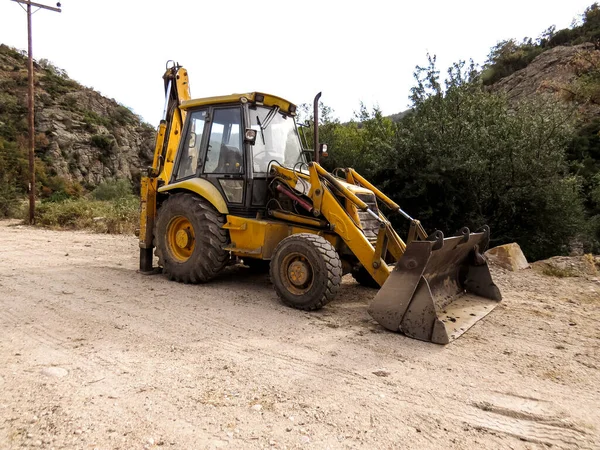 Traktör, nehir çalışmaları, yol genişlemesi. Bir nehir yatağında çalışan traktör yol genişlemesini ve baraj bakımını destekliyor. Arazi temizliği, su kontrolü ve yerel altyapı projelerinin inşası için ağır ekipmanlar.