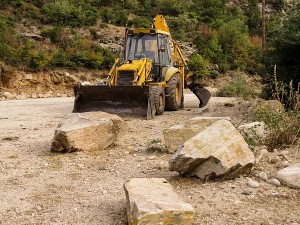 Traktör, nehir çalışmaları, yol genişlemesi. Bir nehir yatağında çalışan traktör yol genişlemesini ve baraj bakımını destekliyor. Arazi temizliği, su kontrolü ve yerel altyapı projelerinin inşası için ağır ekipmanlar.