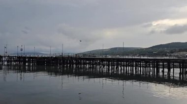 Gri bir günde sakin bir suda iskele.