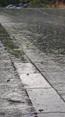 Sokakta yağmur yağıyor. Yağmurda ıslak bir yolda araba sürüyor.