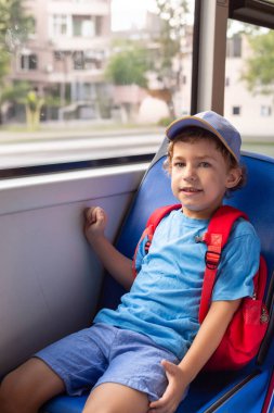 Otobüse binen genç bir çocuk. Küçük çocuk sandalyede oturuyor.